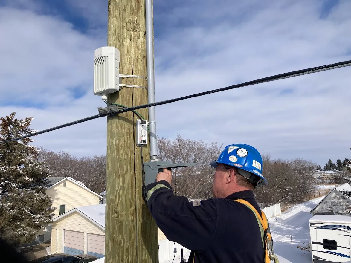 A Connect Mobility technician installing network equipment on a utility pole in winter